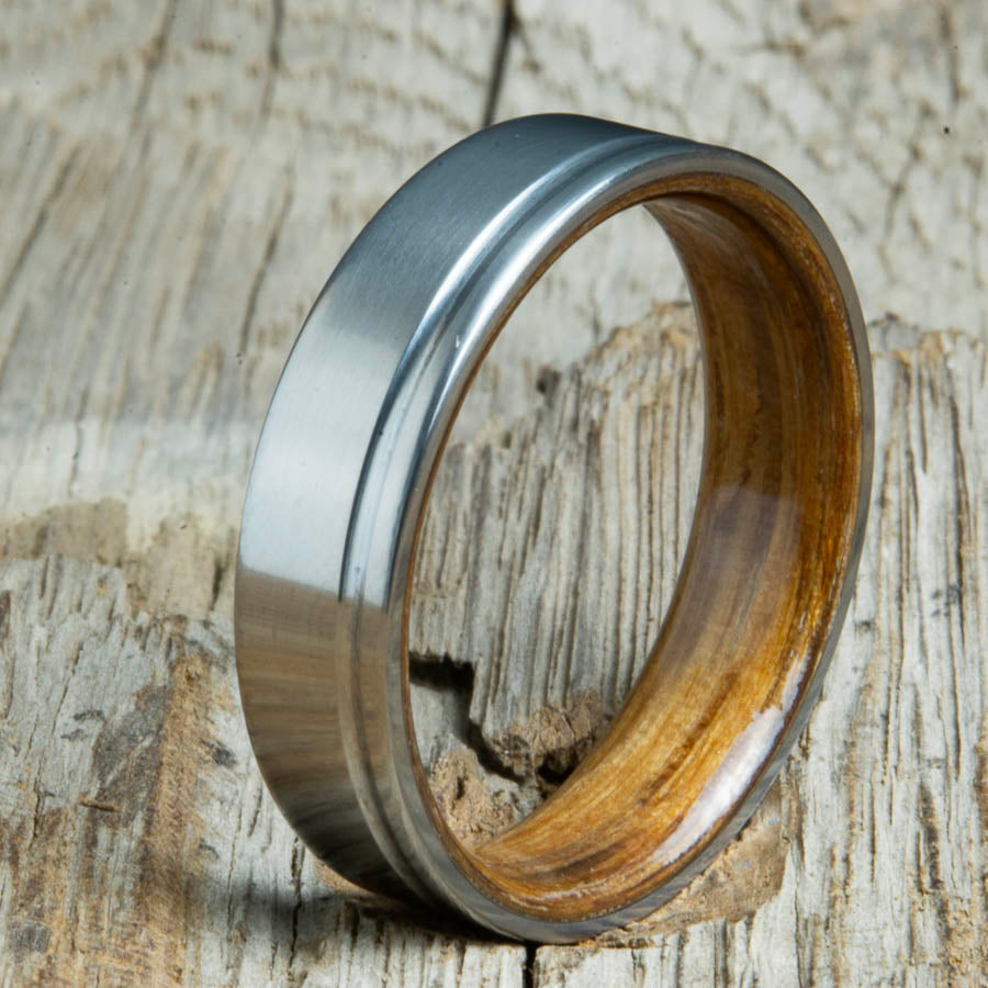 Single groove satin titanium wood ring with Whiskey barrel wood interior. Custom titanium wood rings handcrafted by Peacefield Titanium