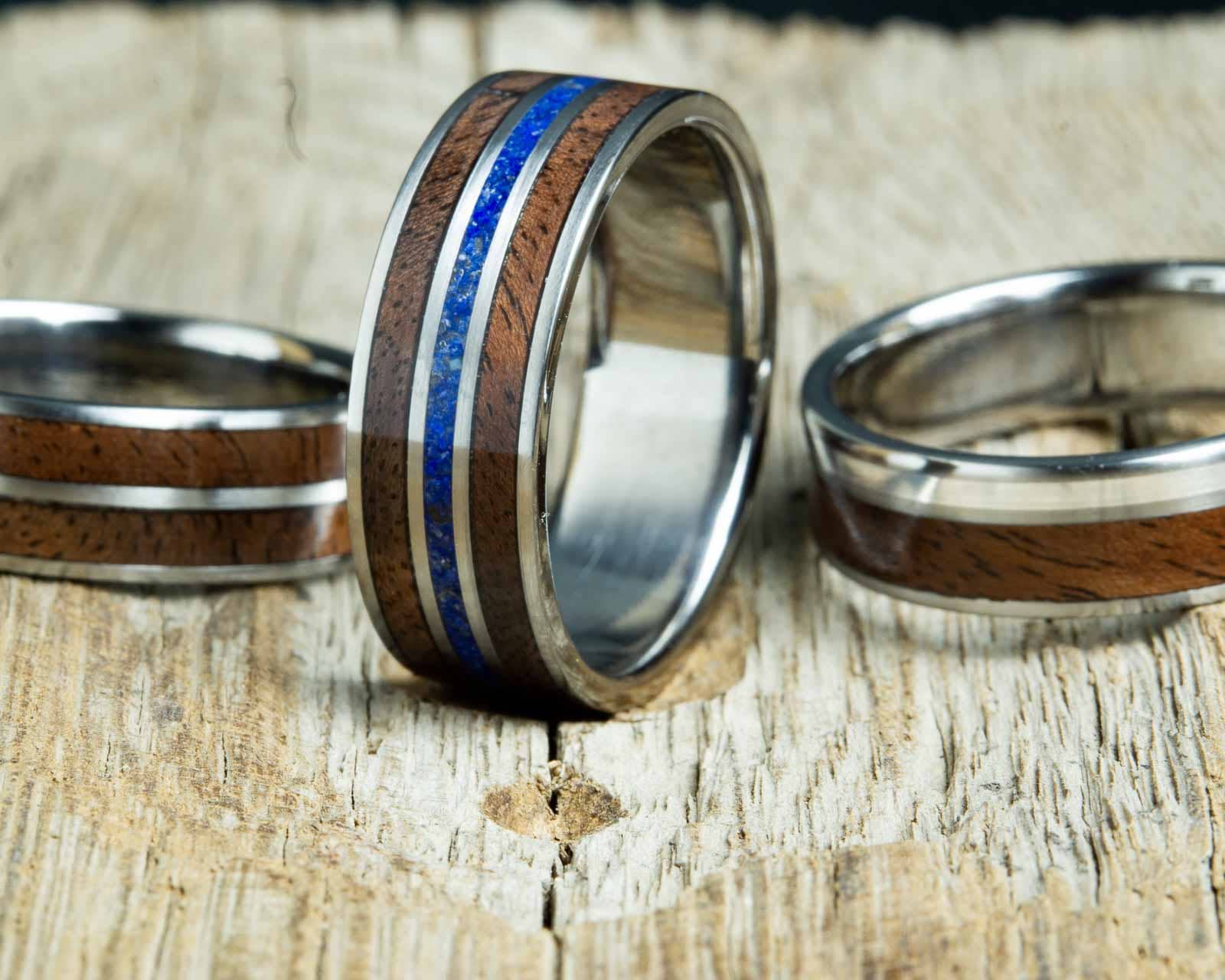 Collection of custom rings made with reclaimed Black Walnut wood and various inlays like silver, copper, and natural stones made by Peacefield Titanium 