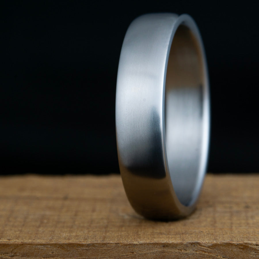 Silver ring on a textured surface with a dark background