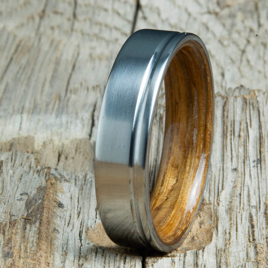 Single groove satin titanium wood ring with Whiskey barrel wood interior. Custom titanium wood rings handcrafted by Peacefield Titanium