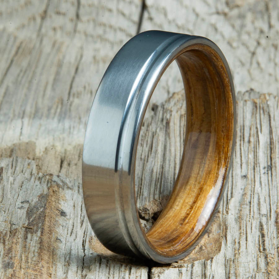 Single groove satin titanium wood ring with Whiskey barrel wood interior. Custom titanium wood rings handcrafted by Peacefield Titanium