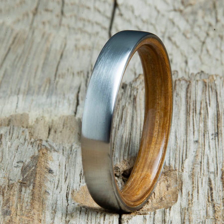 Whiskey barrel lined womens wood ring with satin titanium. Custom handcrafted womens wooden rings are made by Peacefield Titanium