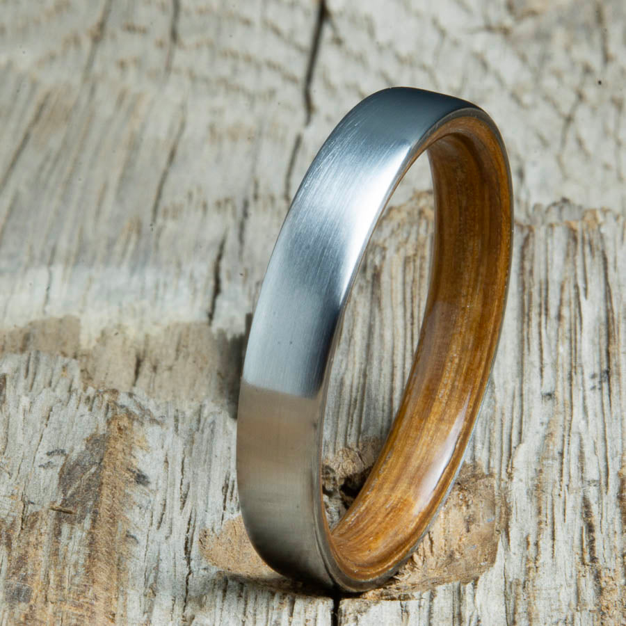 Whiskey barrel lined womens wood ring with satin titanium. Custom handcrafted womens wooden rings are made by Peacefield Titanium