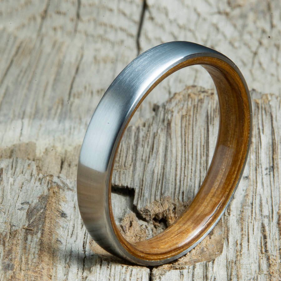 Whiskey barrel lined womens wood ring with satin titanium. Custom handcrafted womens wooden rings are made by Peacefield Titanium