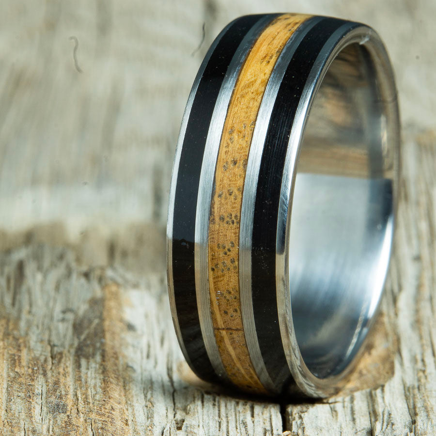 whiskey barrel wood inlay ring with volcanic sand. Custom made wood and titanium ring made by Peacefield Titanium.